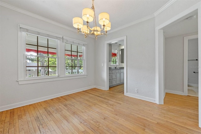 spare room featuring sink, a notable chandelier, ornamental molding, and light hardwood / wood-style floors