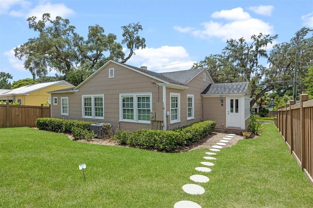 rear view of house featuring central AC unit and a lawn