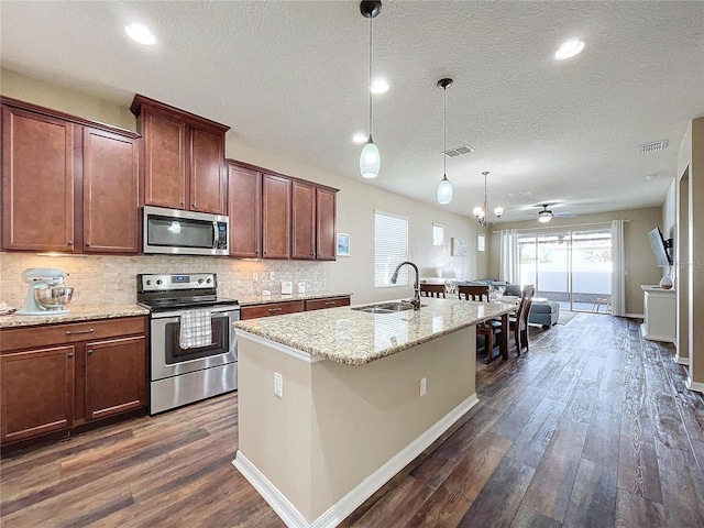 kitchen featuring a kitchen island with sink, ceiling fan with notable chandelier, sink, appliances with stainless steel finishes, and dark hardwood / wood-style flooring