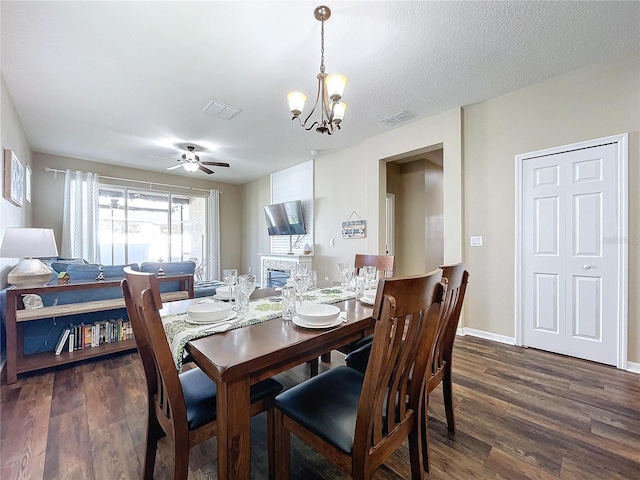 dining area featuring ceiling fan with notable chandelier, a textured ceiling, and dark hardwood / wood-style flooring