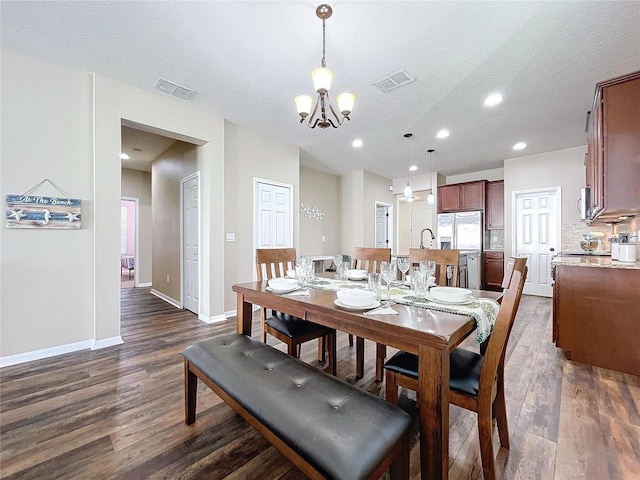 dining area with a textured ceiling, dark hardwood / wood-style floors, and a notable chandelier