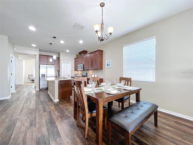 dining area featuring a wealth of natural light, dark wood-type flooring, a textured ceiling, and a notable chandelier