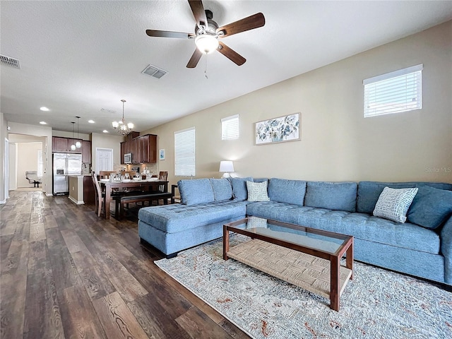 living room with a textured ceiling, ceiling fan with notable chandelier, and dark hardwood / wood-style floors