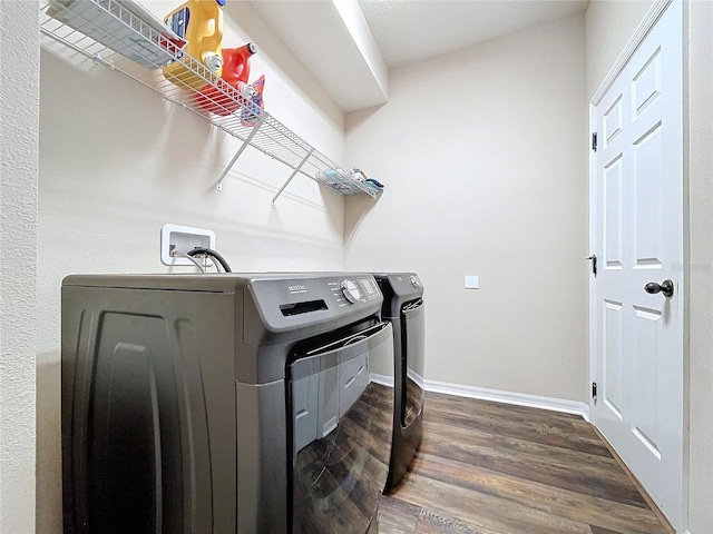 clothes washing area with separate washer and dryer and dark wood-type flooring