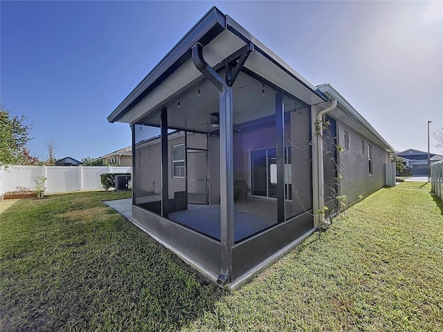 view of side of home with central AC, a lawn, and a sunroom