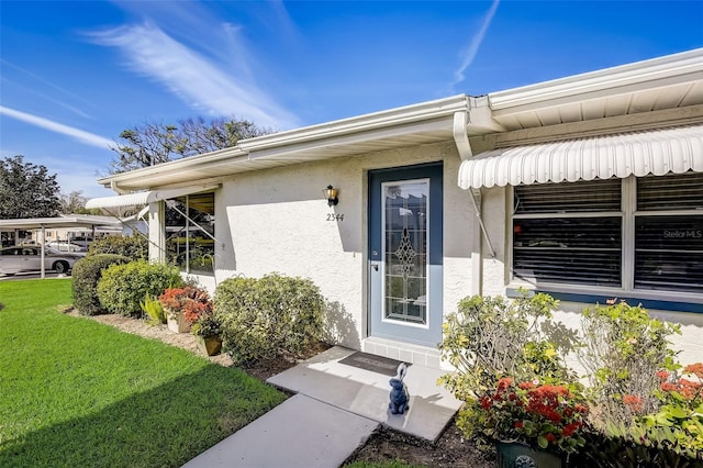 doorway to property featuring a yard and stucco siding