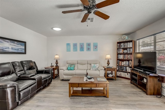 living room with ceiling fan, a textured ceiling, and light hardwood / wood-style flooring