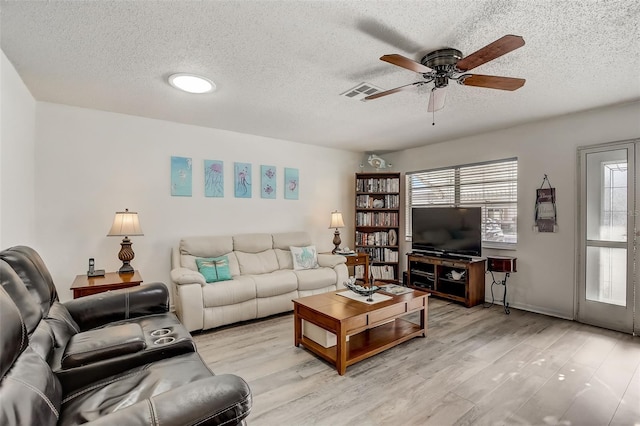 living room featuring light hardwood / wood-style floors, a textured ceiling, and ceiling fan