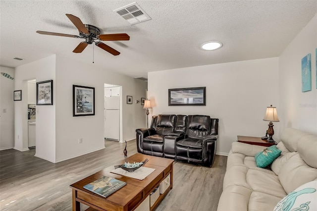 living room featuring light hardwood / wood-style floors, a textured ceiling, and ceiling fan