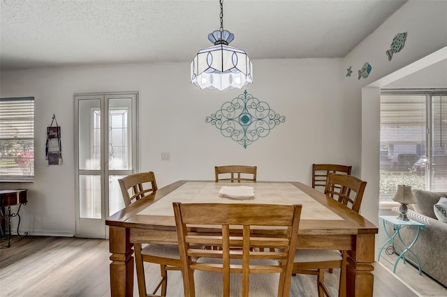 dining area with light wood-style flooring, a textured ceiling, and a wealth of natural light