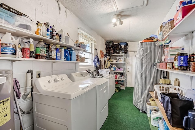 laundry room with water heater, washer and dryer, and a textured ceiling