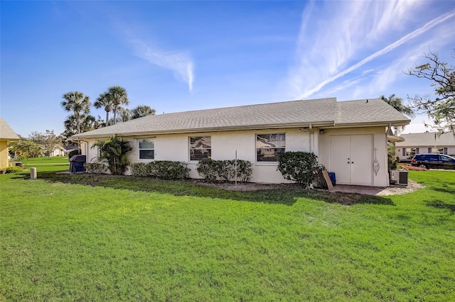 view of front of home with a front lawn, central AC unit, and stucco siding