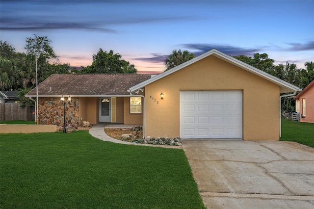 ranch-style house featuring a garage and a yard