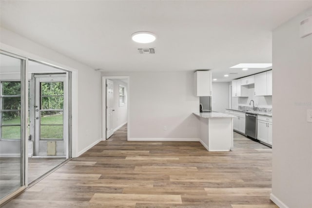 kitchen featuring white cabinetry, light hardwood / wood-style floors, light stone counters, and dishwasher