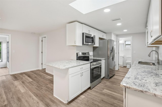 kitchen with appliances with stainless steel finishes, white cabinetry, light wood-type flooring, and sink