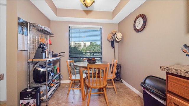 dining space with a raised ceiling and light tile patterned floors