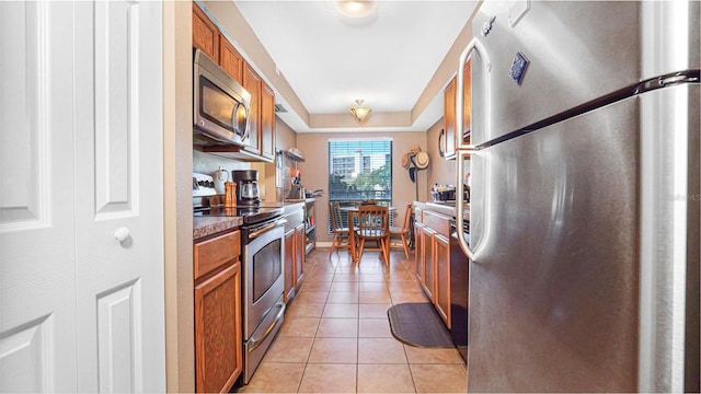 kitchen featuring light tile patterned floors, a raised ceiling, and stainless steel appliances