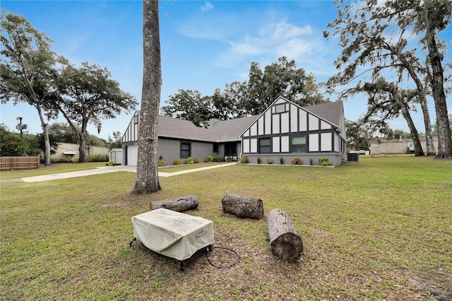 tudor home with central AC, a front lawn, and a garage