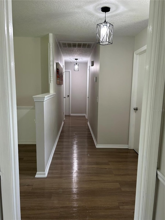 hall featuring a textured ceiling and dark wood-type flooring