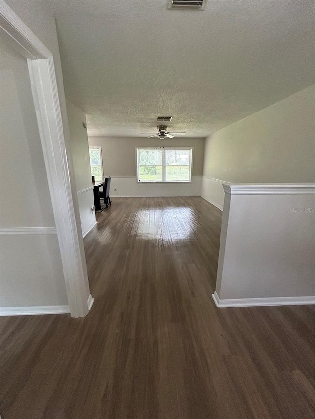 interior space with ceiling fan, a textured ceiling, and dark wood-type flooring