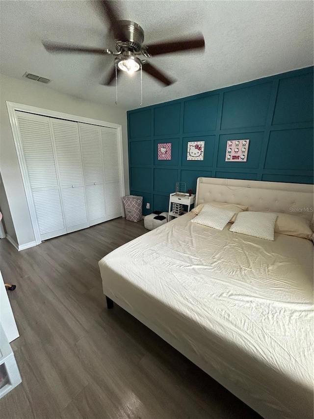 bedroom with a closet, ceiling fan, dark hardwood / wood-style floors, and a textured ceiling