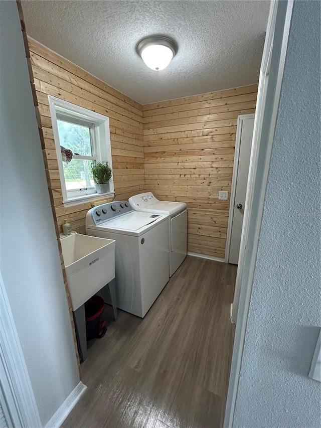 washroom featuring sink, a textured ceiling, wooden walls, separate washer and dryer, and dark hardwood / wood-style flooring