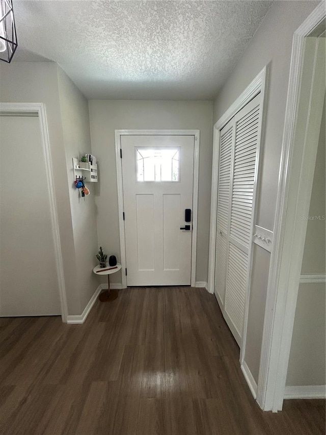 doorway to outside with a textured ceiling and dark hardwood / wood-style floors