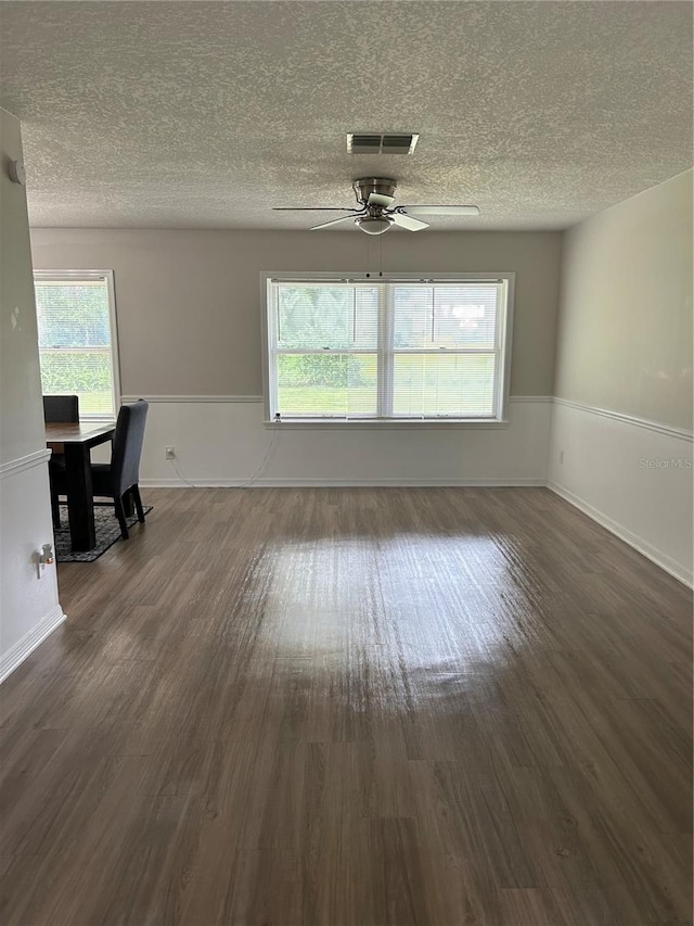 interior space with a textured ceiling, dark wood-type flooring, and a healthy amount of sunlight