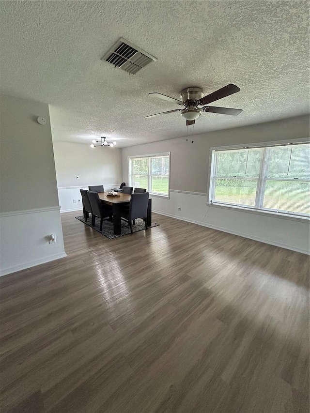 dining space featuring a textured ceiling, dark hardwood / wood-style flooring, and a wealth of natural light