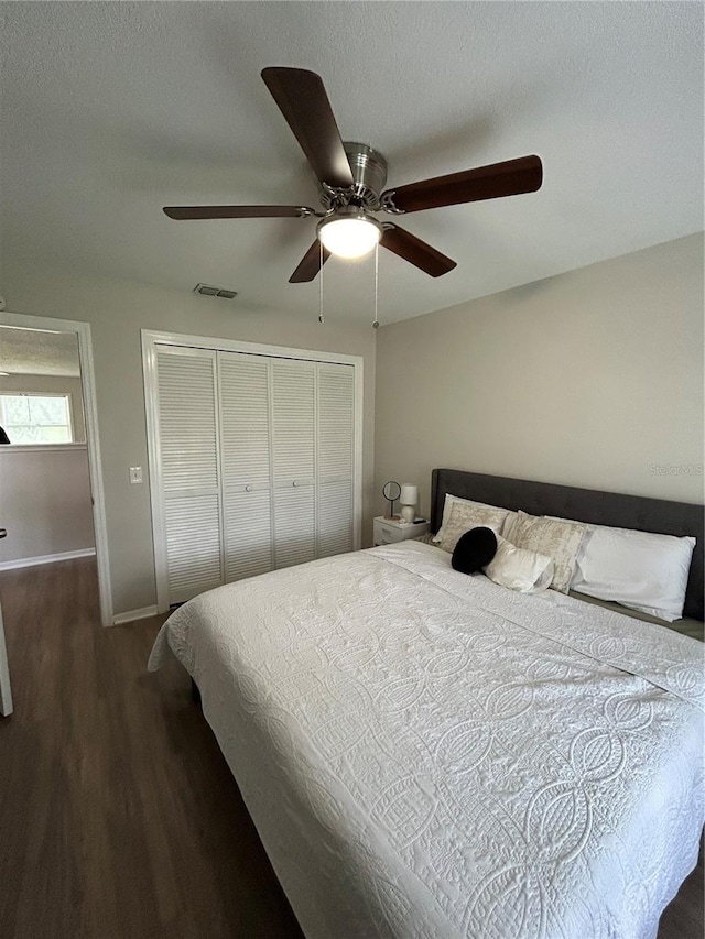 bedroom featuring a textured ceiling, dark hardwood / wood-style floors, ceiling fan, and a closet