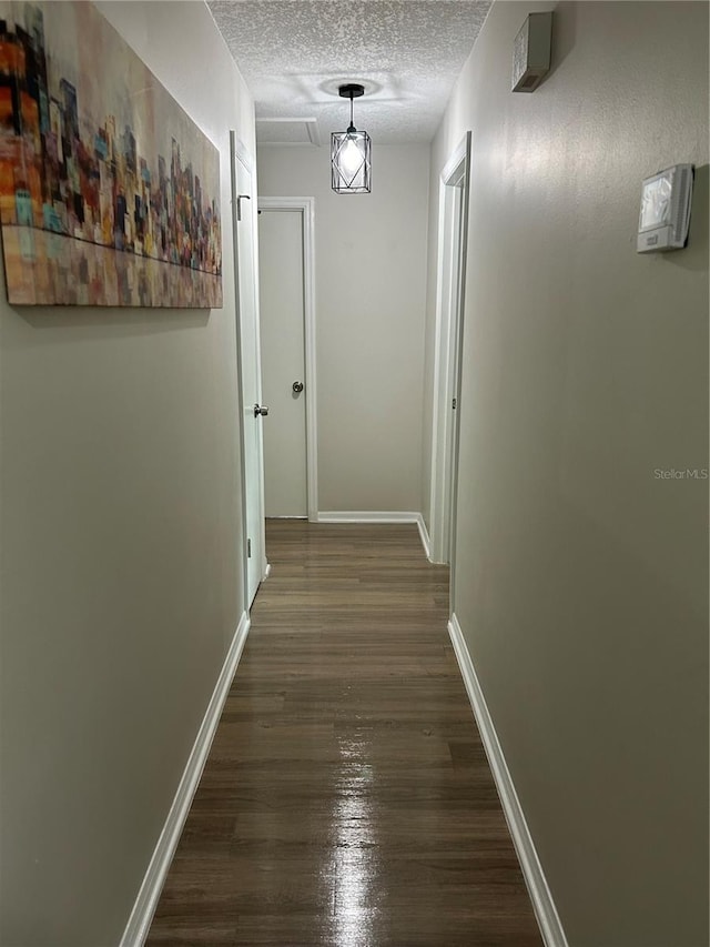 hall with a textured ceiling and dark wood-type flooring