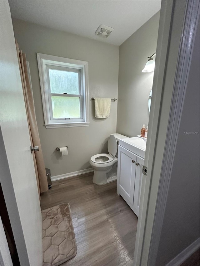 bathroom with vanity, toilet, and hardwood / wood-style flooring