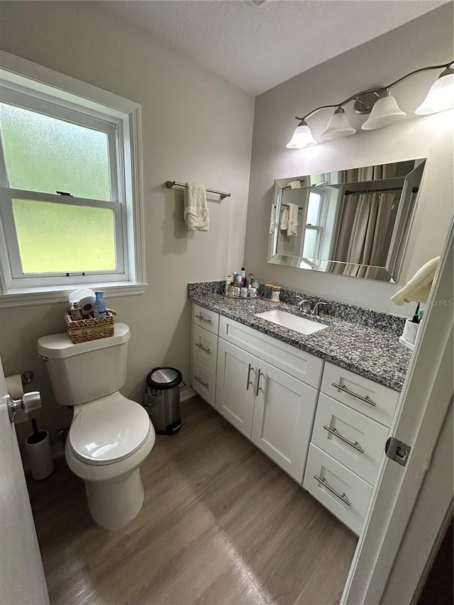 bathroom featuring a textured ceiling, hardwood / wood-style flooring, vanity, and toilet