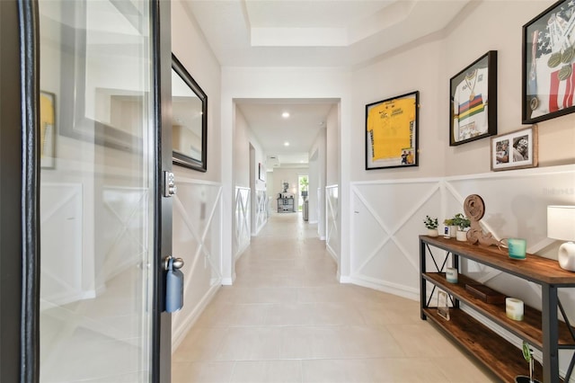 hallway with light tile patterned floors and a tray ceiling