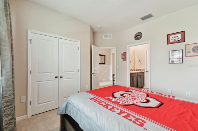 carpeted bedroom with a closet and ensuite bath