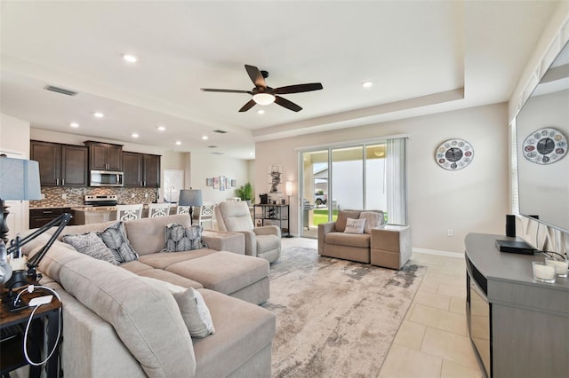 tiled living room featuring ceiling fan and a raised ceiling