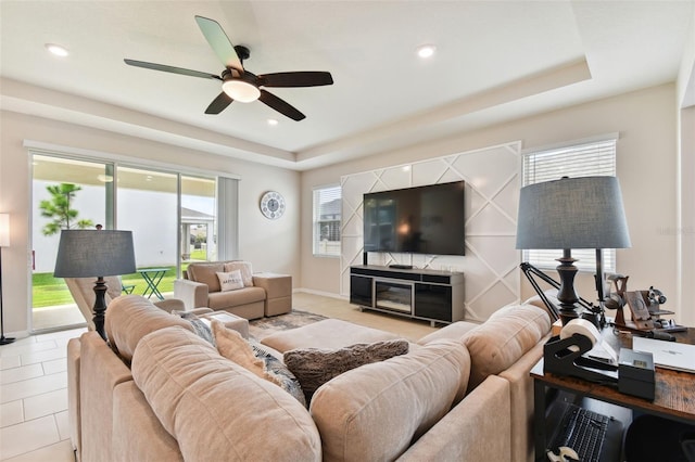 tiled living room featuring ceiling fan and a raised ceiling