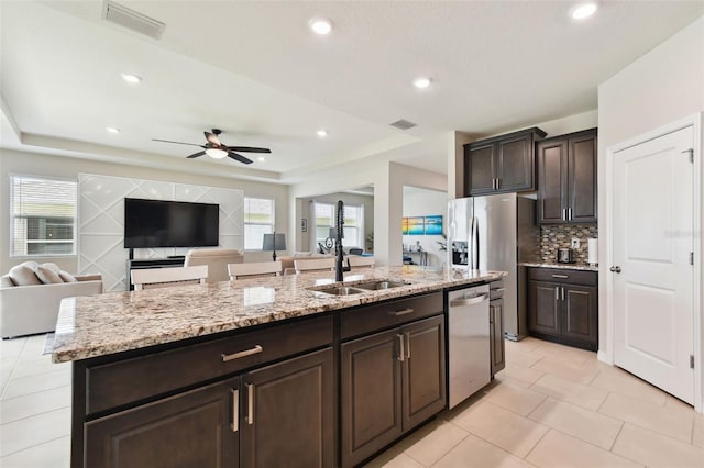 kitchen with stainless steel dishwasher, ceiling fan, a wealth of natural light, and an island with sink