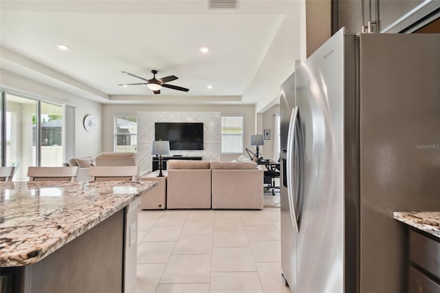 kitchen with plenty of natural light, ceiling fan, a raised ceiling, and stainless steel fridge