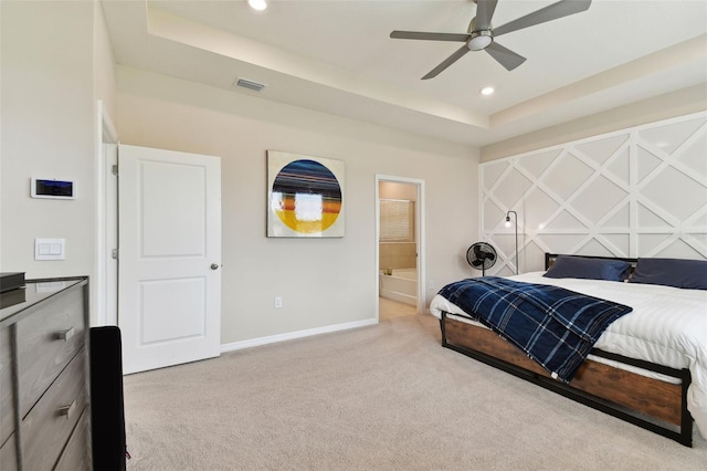 carpeted bedroom featuring ceiling fan, ensuite bathroom, and a tray ceiling