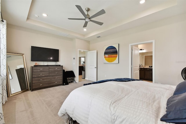 carpeted bedroom featuring ensuite bathroom, ceiling fan, and a raised ceiling