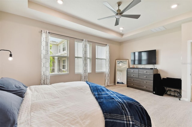 carpeted bedroom featuring ceiling fan and a tray ceiling