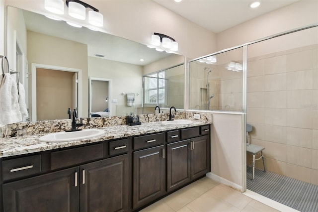 bathroom featuring a shower with door, tile patterned flooring, and dual bowl vanity