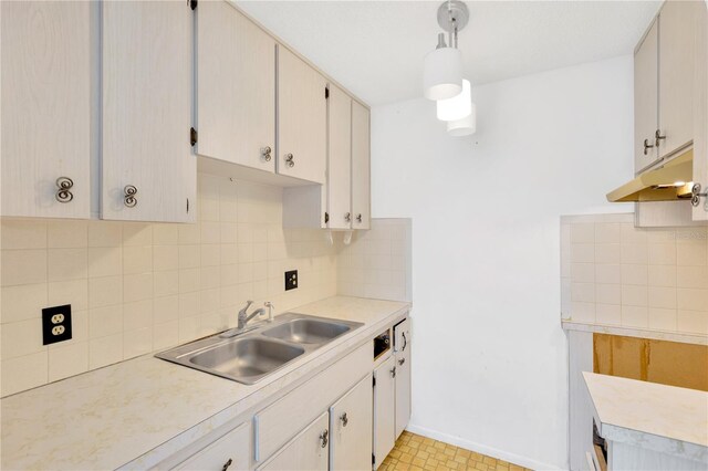 kitchen featuring sink, decorative light fixtures, tasteful backsplash, and light tile patterned floors