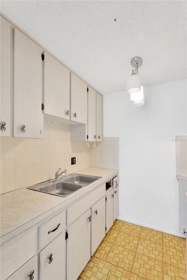 kitchen with sink, pendant lighting, white cabinets, and decorative backsplash