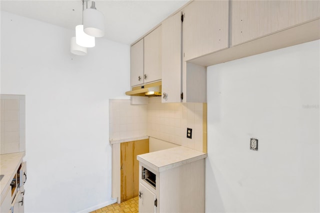 kitchen with decorative backsplash, hanging light fixtures, and light tile patterned floors