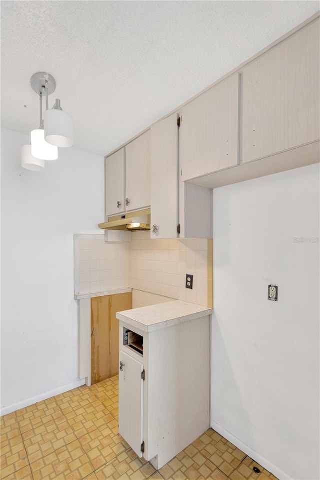 kitchen featuring decorative backsplash, decorative light fixtures, and light tile patterned floors