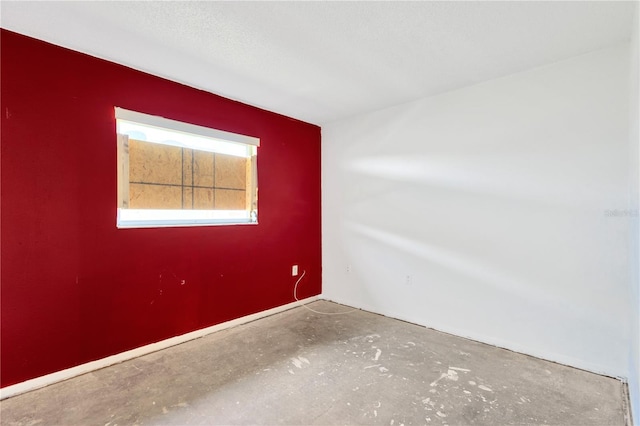 unfurnished room with a textured ceiling and concrete flooring