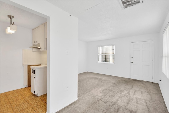 spare room featuring light carpet and a textured ceiling