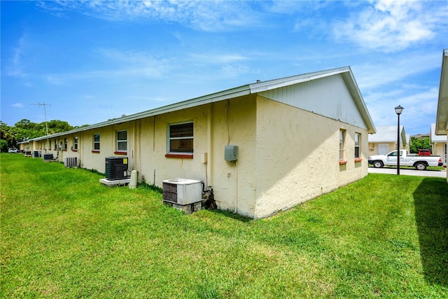 rear view of house featuring central AC and a lawn